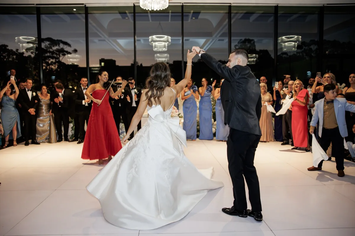 Bride and groom first dance at a Sydney wedding reception, surrounded by guests and live violin