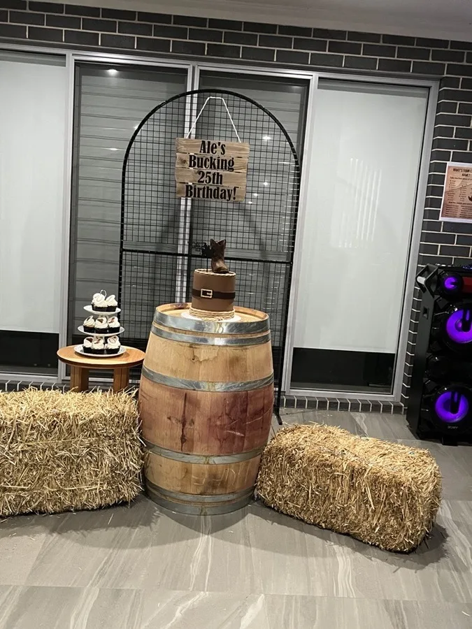 Country themed 25th birthday styling with a wine barrel cake stand and hay bales